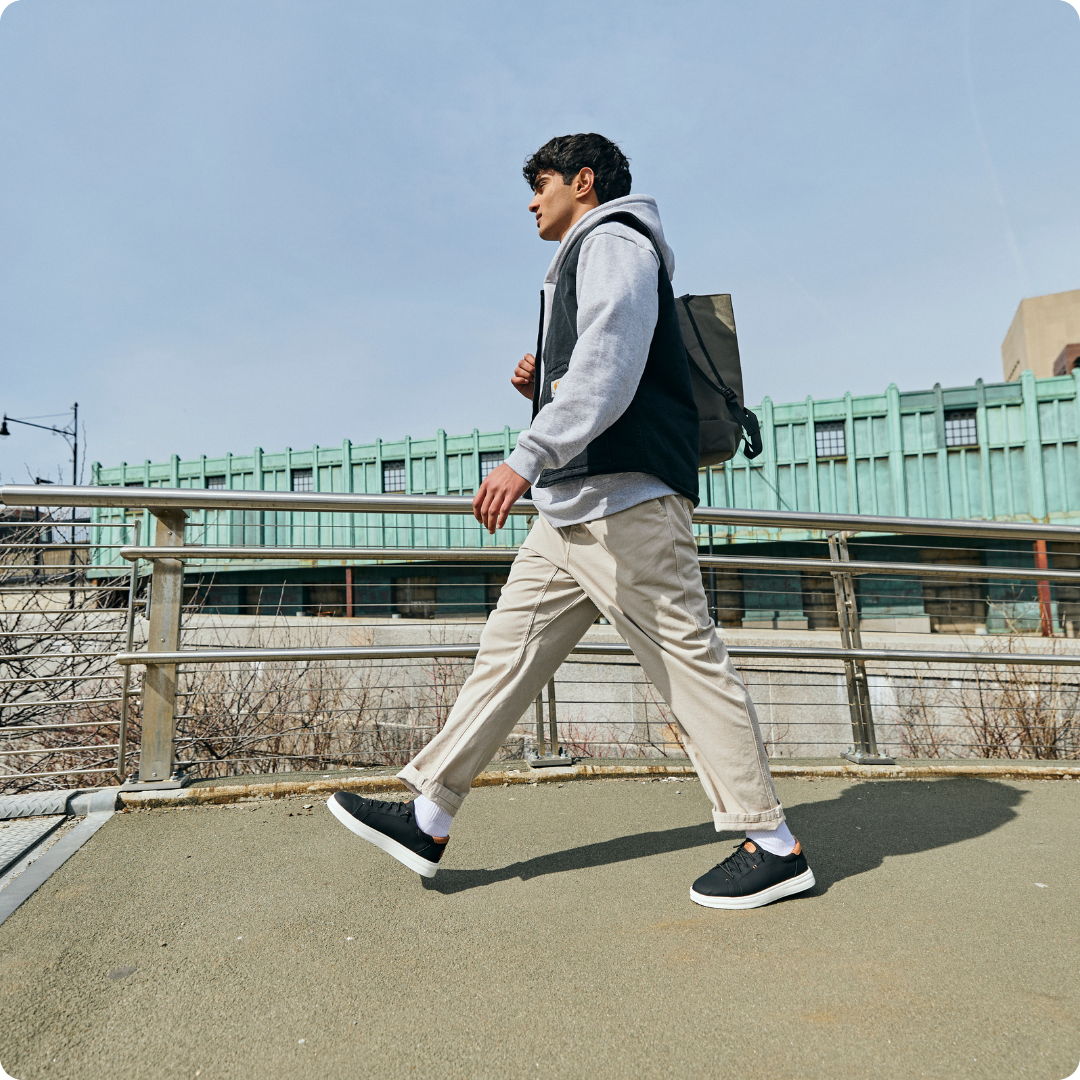 A person walking on a path wearing casual clothes and sneakers.