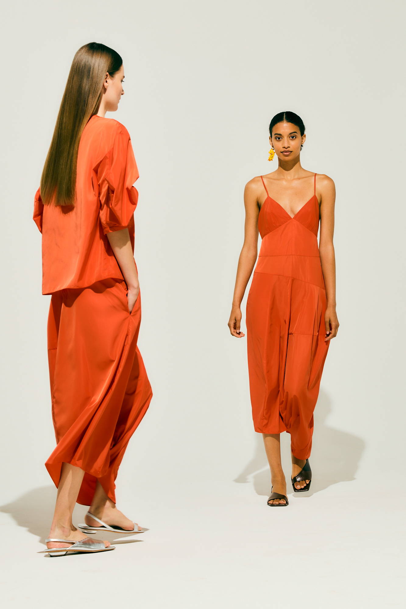 Two models wearing red outfits on a neutral background.