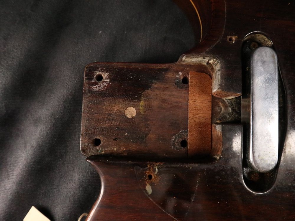 Close-up of a guitar neck joint showing wood and metal components.