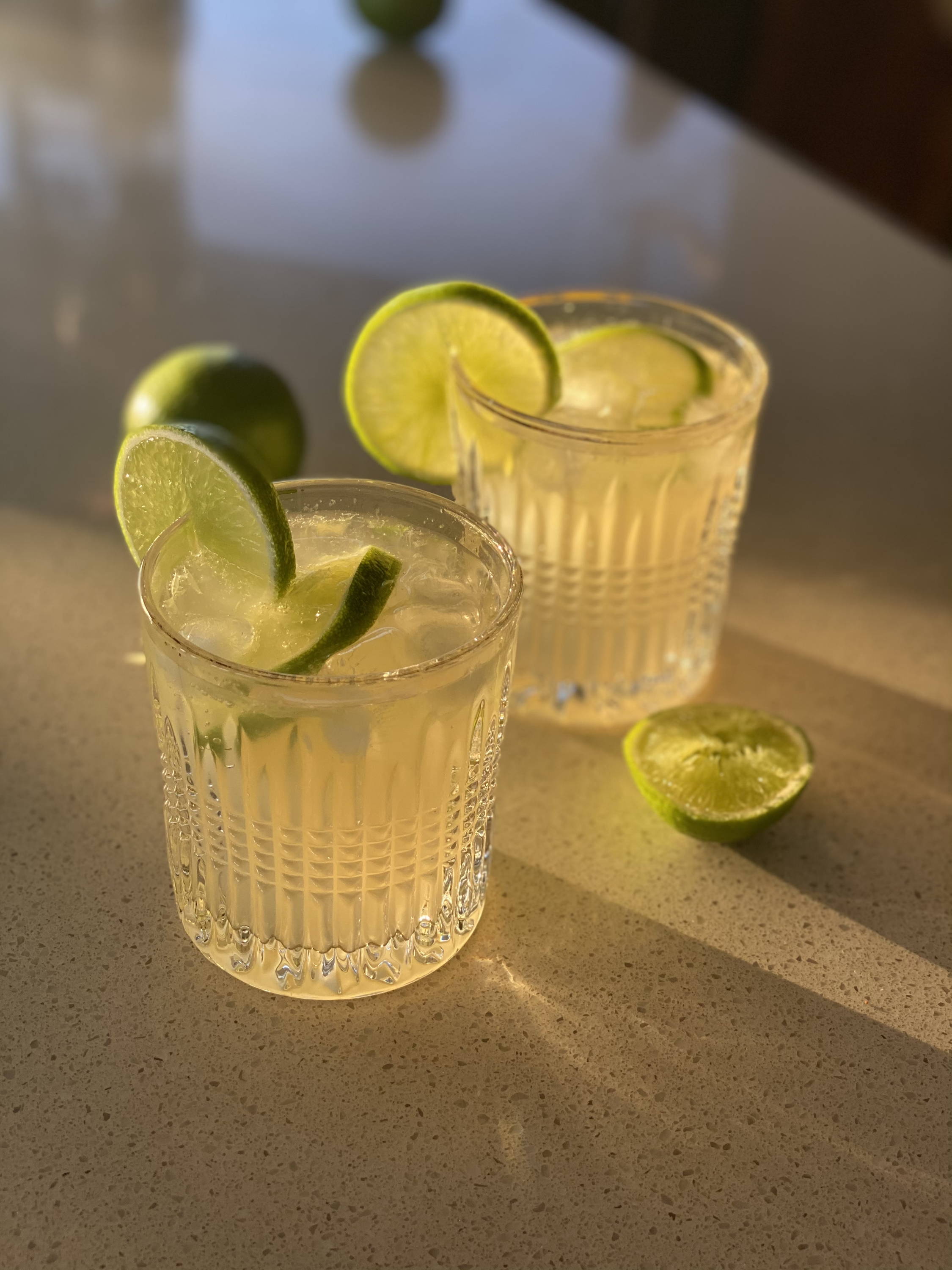 Two mexican mule cocktails on a kitchen bench with lime slices