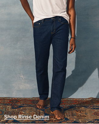 Person wearing dark jeans and a white shirt on a patterned rug.