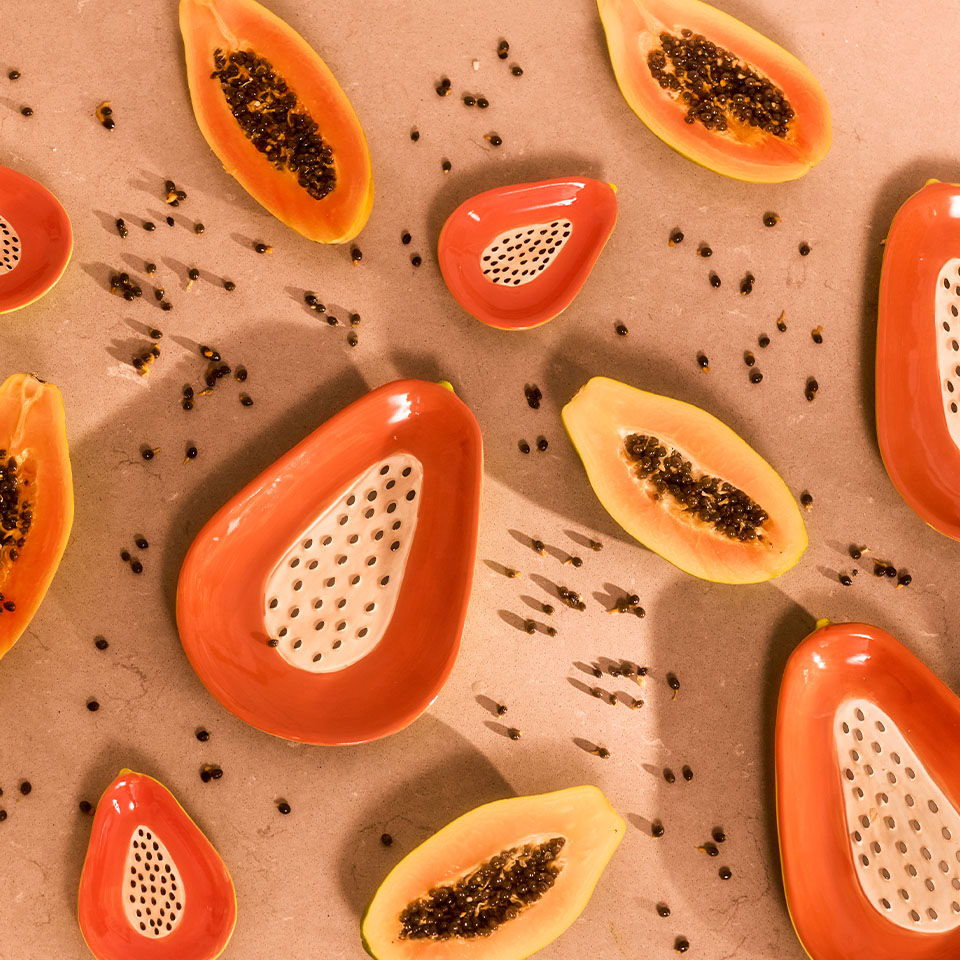 Sliced papayas arranged on a brown surface, showcasing seeds and vibrant colors.