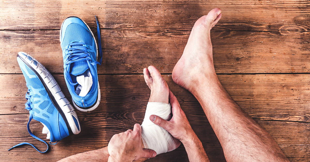 man putting bandage on his ankle sprain