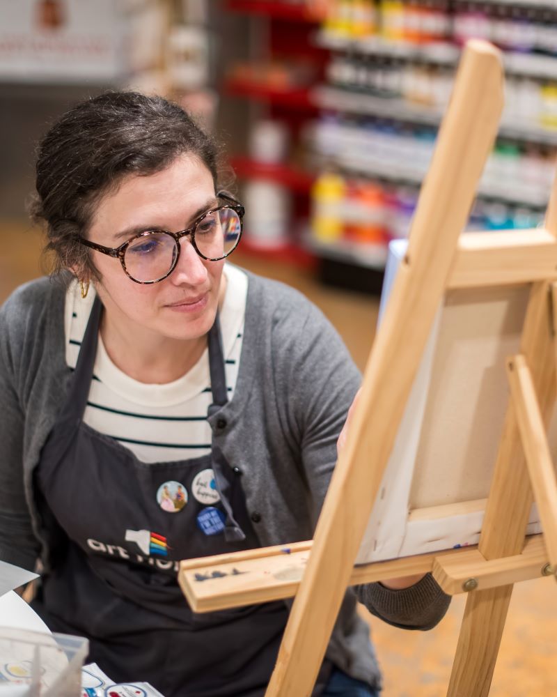 Woman painting on an easel in an art supply store.