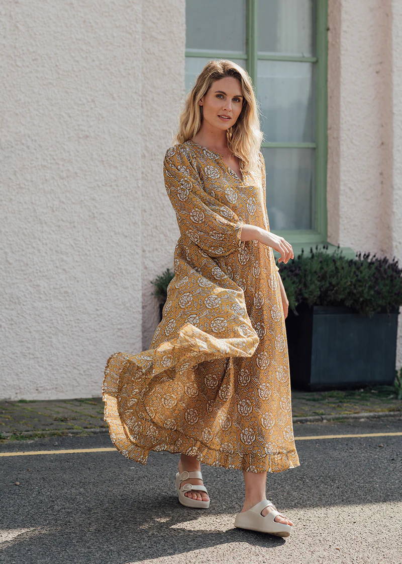 A model wearing a yellow, floaty floral dress with off white chunky platform slides