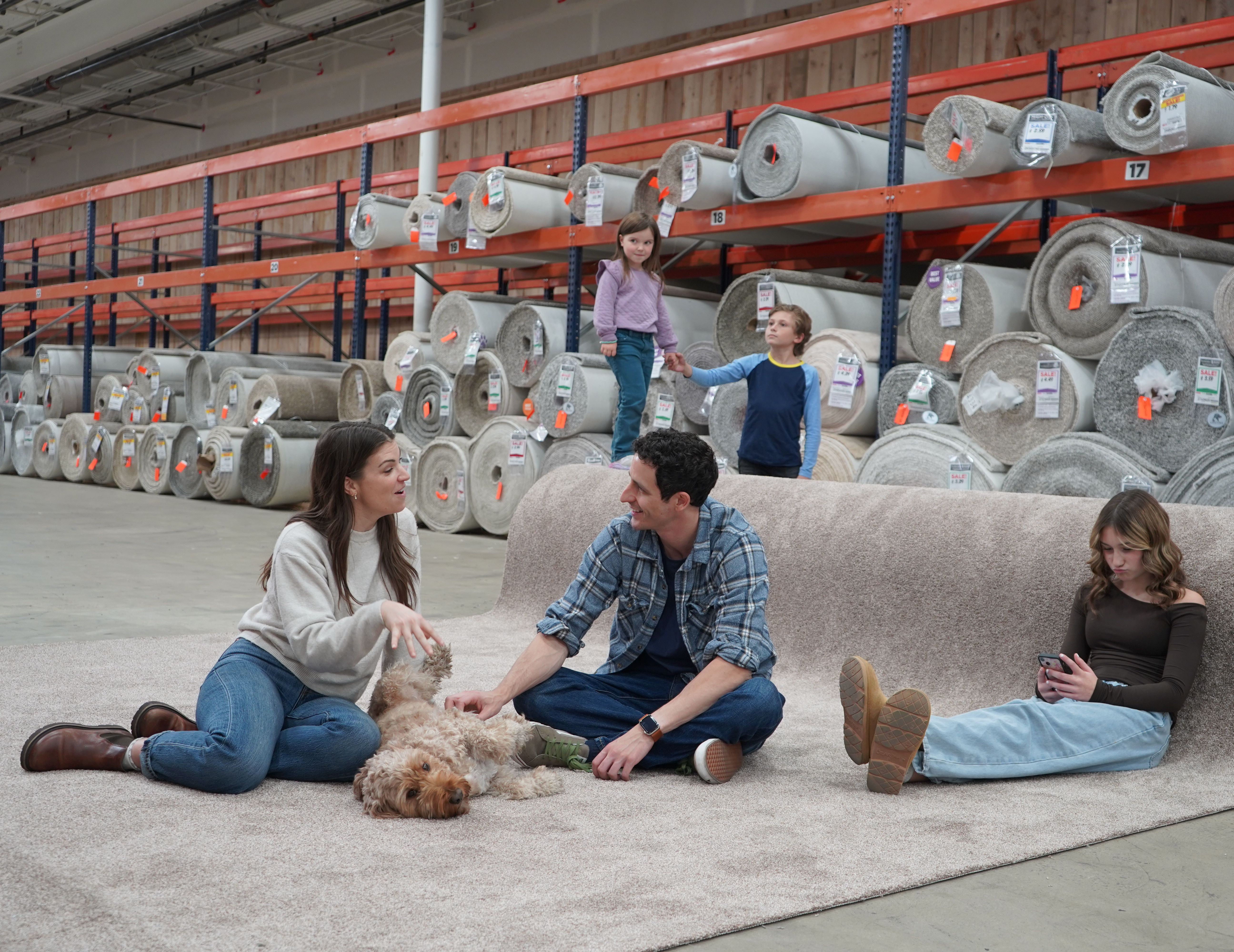 family sitting on carpet to test in flooring store