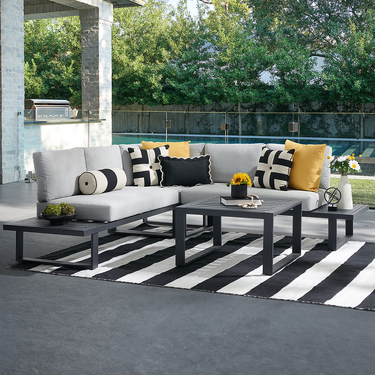 Outdoor seating area with a sectional sofa, coffee table, and striped rug.