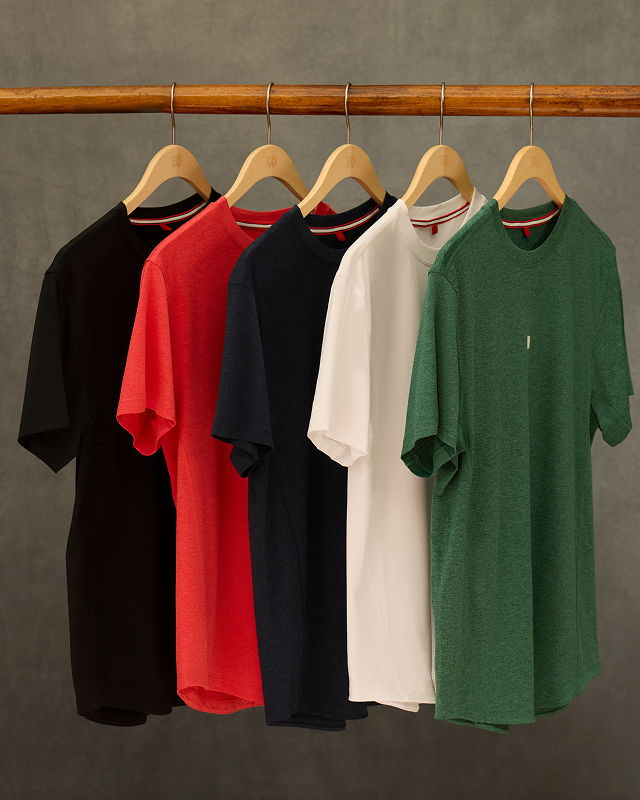 Five short-sleeve t-shirts in various colors hanging on wooden hangers.