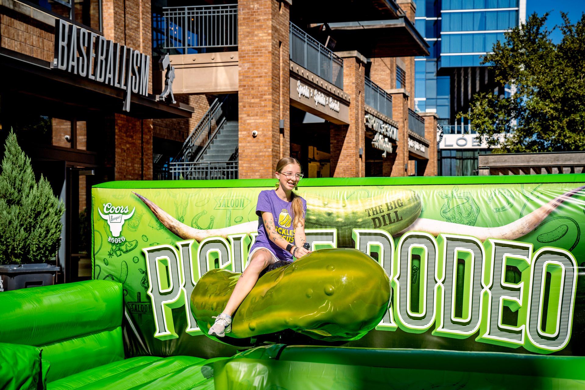 A young guest rides the Coors Banquet Pickle Rodeo mechanical pickle activation at The Big Dill pickle festival, Globe Life Field and Texas Live!, Arlington Texas 2025.