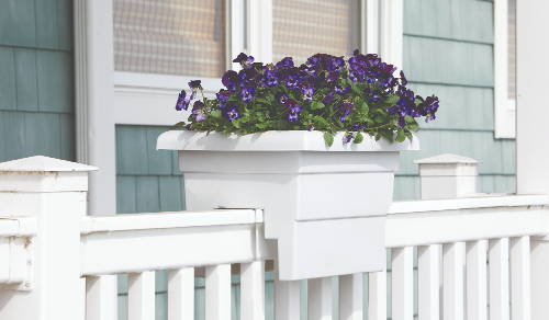 White railing planter with purple flowers on a front porch railing
