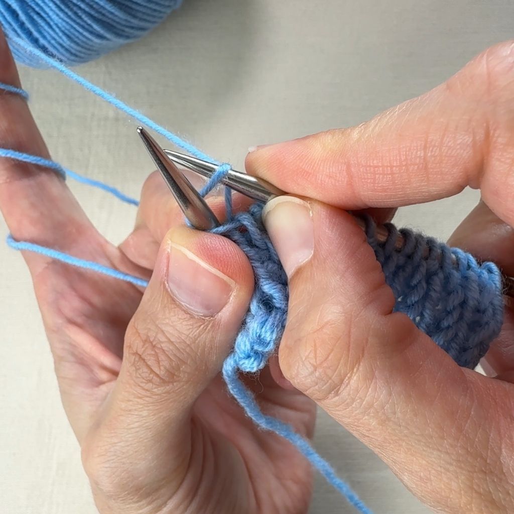 Rechtsverschränkt stricken: Die rechte Nadel strickt von hinten in die Masche ein.