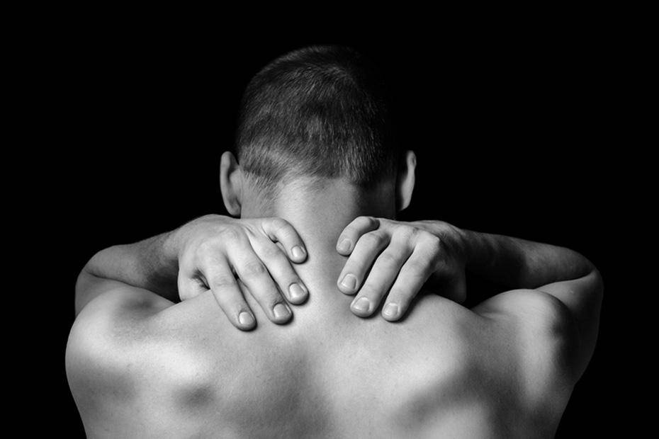 Young man massaging his back to relieve pain