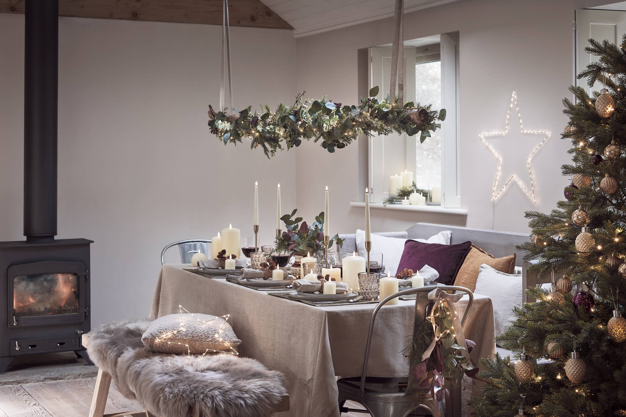 A Christmas dining room with LED star lights, candles, Christmas trees and faux foliage garlands 