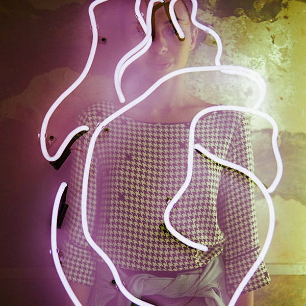 Fotografia de uma imagem abstrata formada por luzes de led, ao fundo das luzes há uma mulher