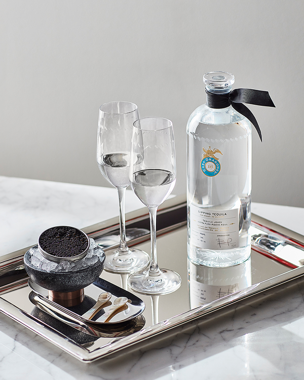 Two glasses and a bottle of water on a silver tray.