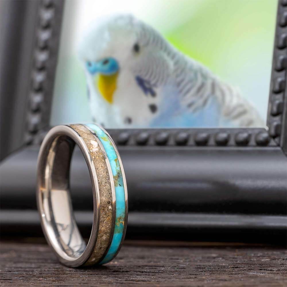 A decorative ring in front of a framed photo of a budgie.