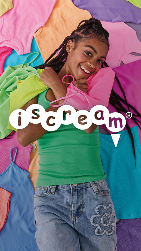 Young woman in colorful clothing, smiling against a vibrant background of shirts.