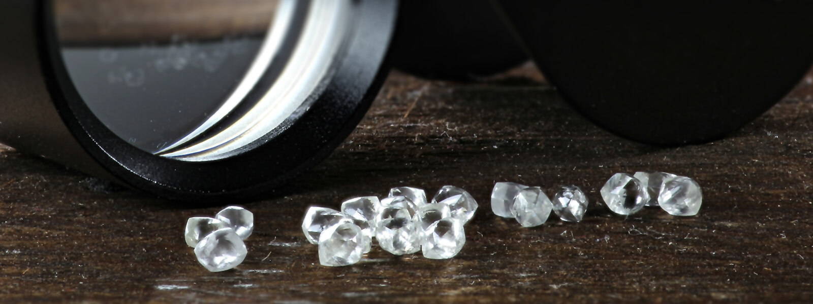 Pile of diamonds near a gemologist's loupe