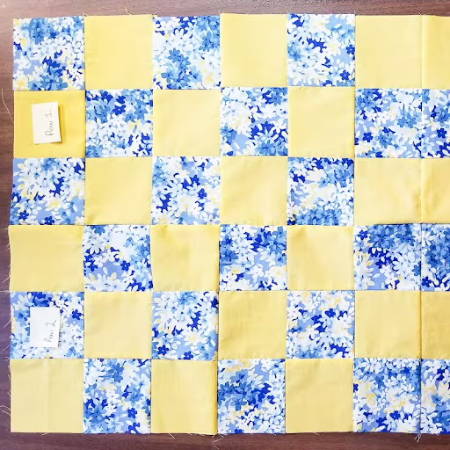 assembling a quilt by sewing together different blocks with square fabric pieces in matching colors