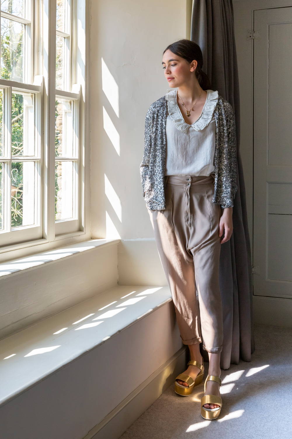 Model wearing silk blouse, neutral trousers and sequin jacket.