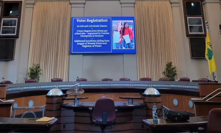 Empty legislative chamber with a screen displaying information and a Brazilian flag.