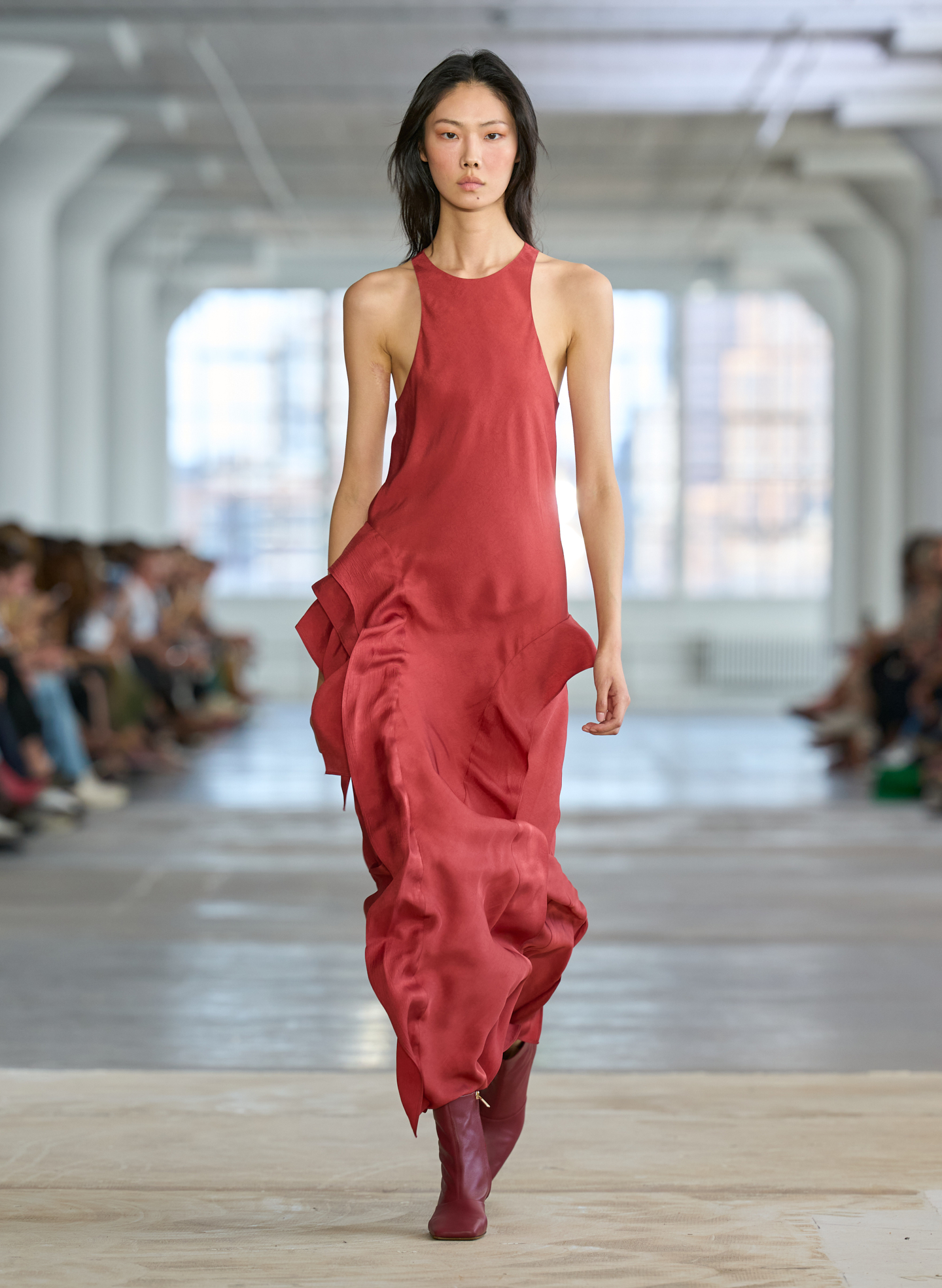 Model walking on runway in a flowing red dress.