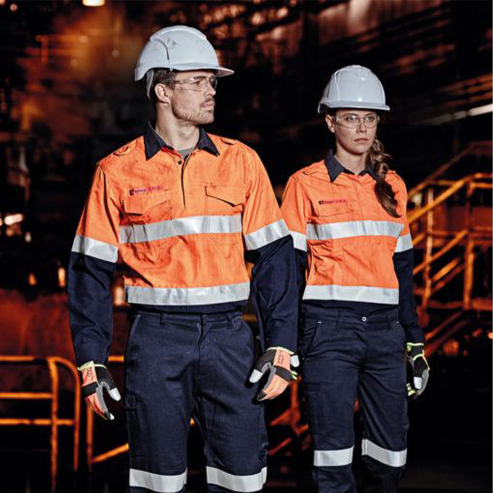 Two workers in safety gear standing in an industrial setting.