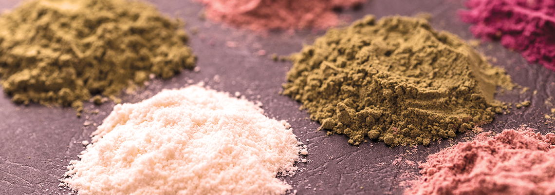 Various colorful powdered spices arranged in mounds on a surface.