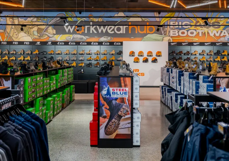Store interior displaying workwear, boots, and clothing items on shelves.
