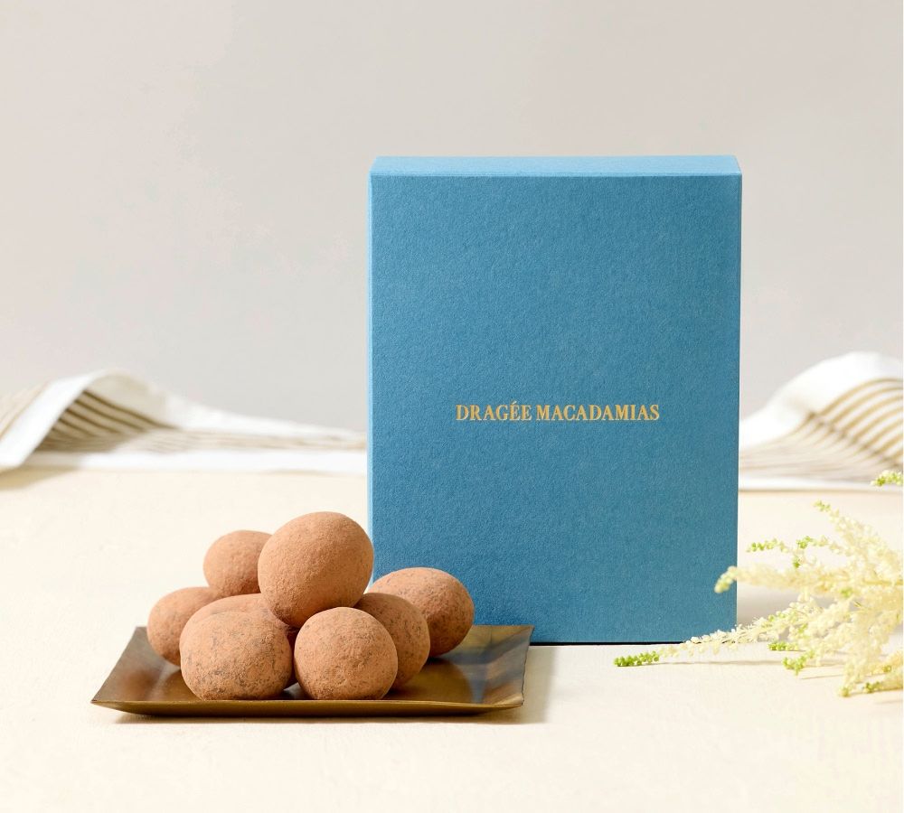 Box of chocolates next to a plate of chocolate truffles.