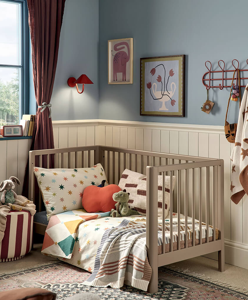Cozy nursery with cotbed, colorful bedding, and decorative wall art.