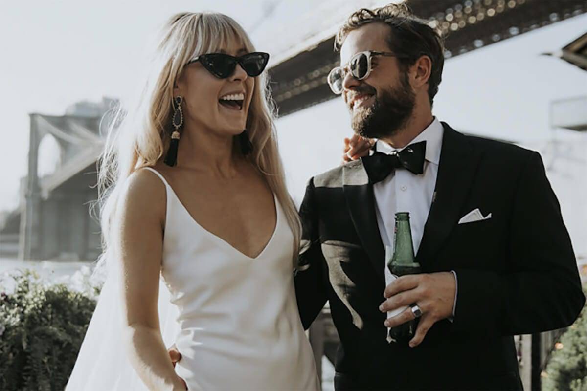 Bride wearing black cat eye sunglasses and groom wearing a black bow tie