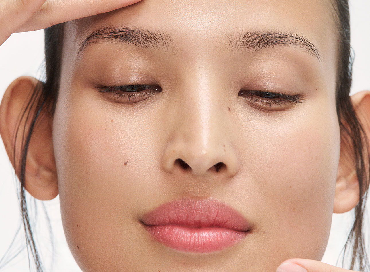 Close-up of a woman gently touching her forehead with a serene expression.
