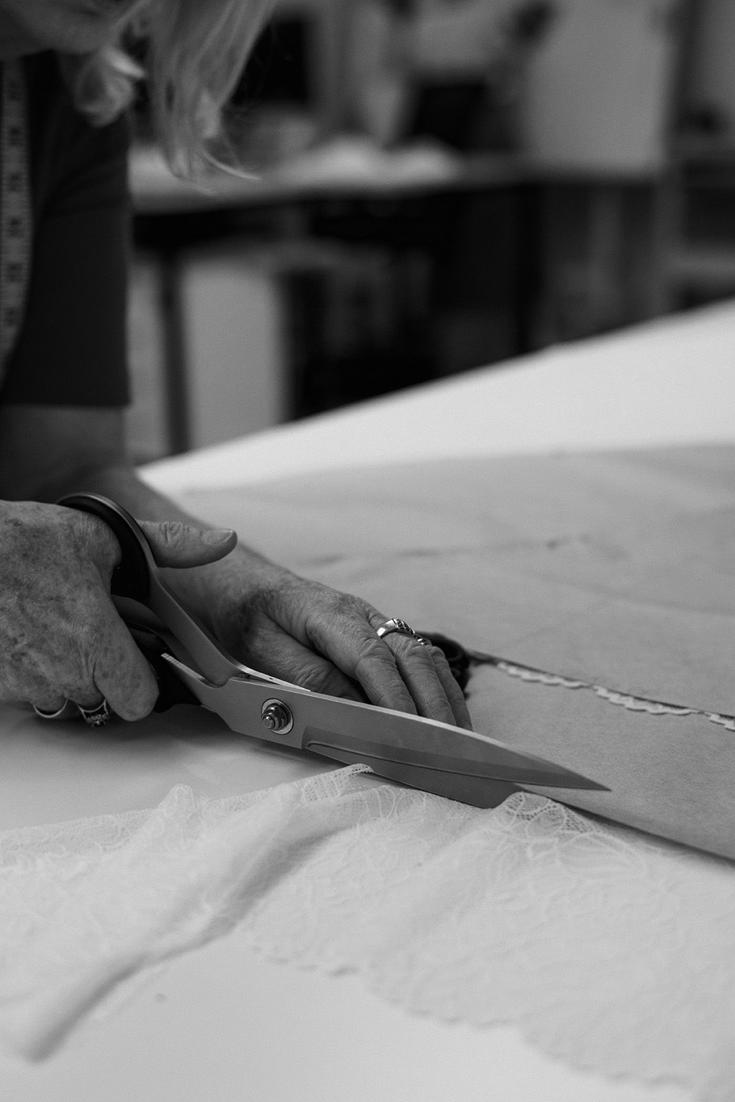 A person cutting fabric with scissors on a table.