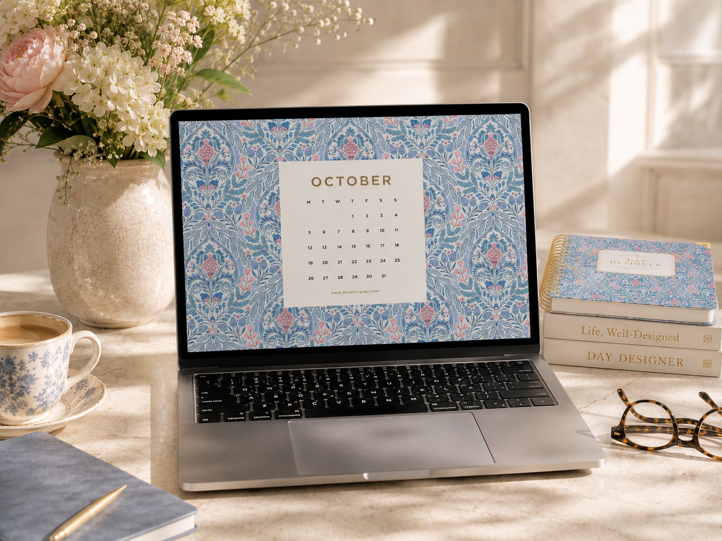 october digital wallpaper shown on a laptop, repeated blue and pink pattern, table, glasses, planner, books, tea cup, flowers in vase