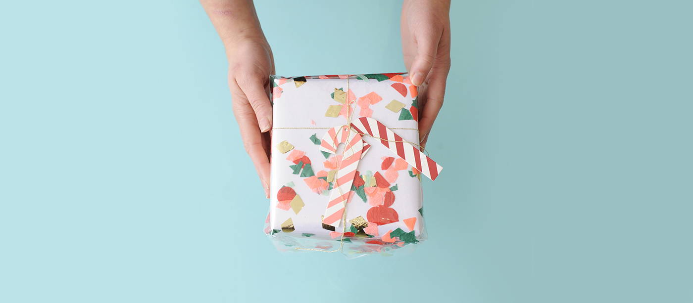 A styled image of two hands holding a beautifully gift wrapped present.