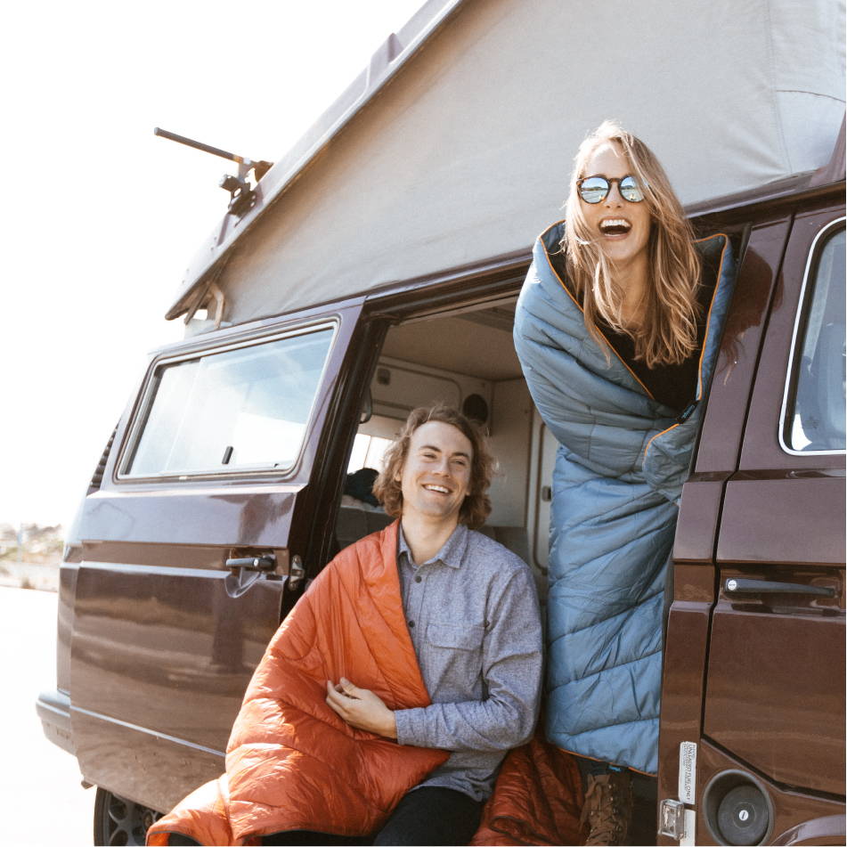 Two people in a camper van wrapped in a Rumpl blanket