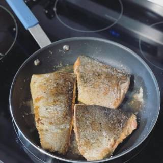 A Misen Nonstick Pan sears salmon, skin side up, on a stovetop.