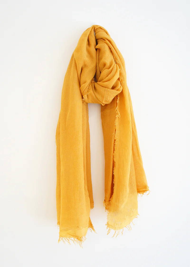 A mustard yellow bamboo scarf with raw edge detailing