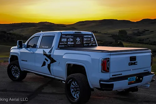 Rear three-quarter view of white GMC truck at sunset