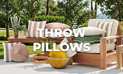 Wooden seating with various decorative throw pillows in a garden setting.
