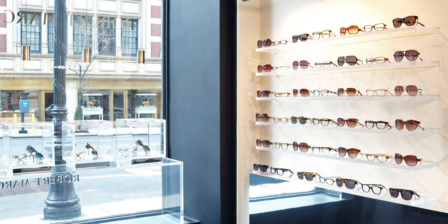 Display of sunglasses in a store window, with a city view outside.
