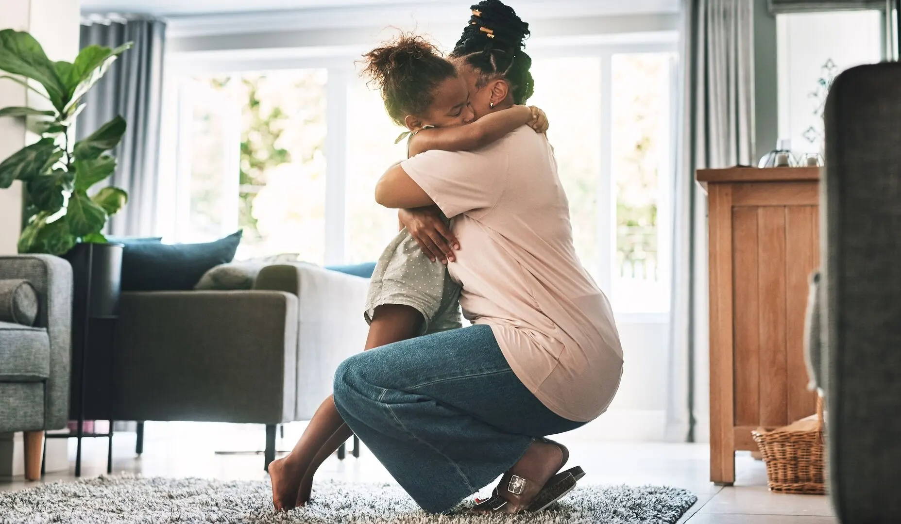 Mom crouching down and hugging her daughter – the kid is longing to go out to play but she has hay fever so has to stay home