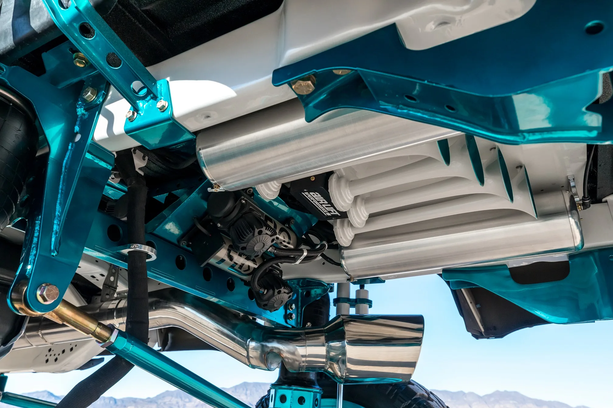 Close-up of white train horn and teal frame components under Ford Super Duty