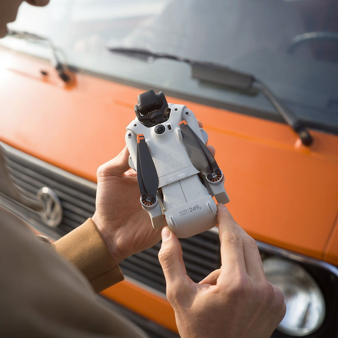 Person inserting a battery into a DJI Lito X1 drone in front of an orange van.