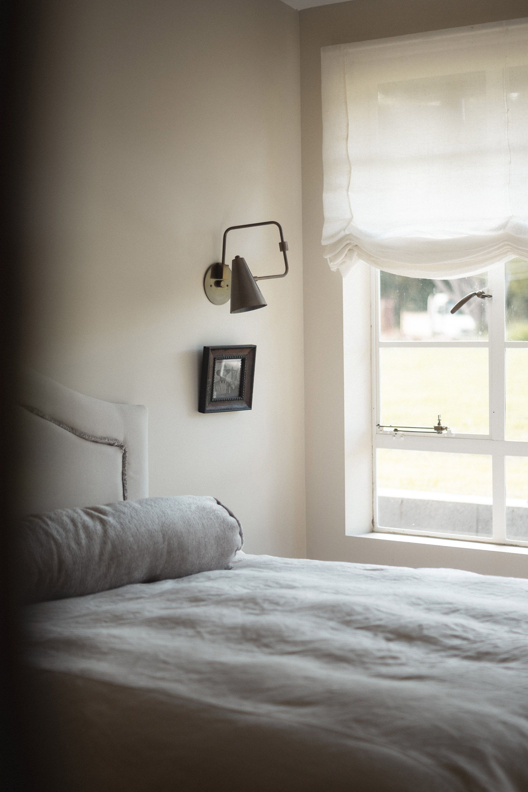 Cozy bedroom with a bed, wall lamp, and window.