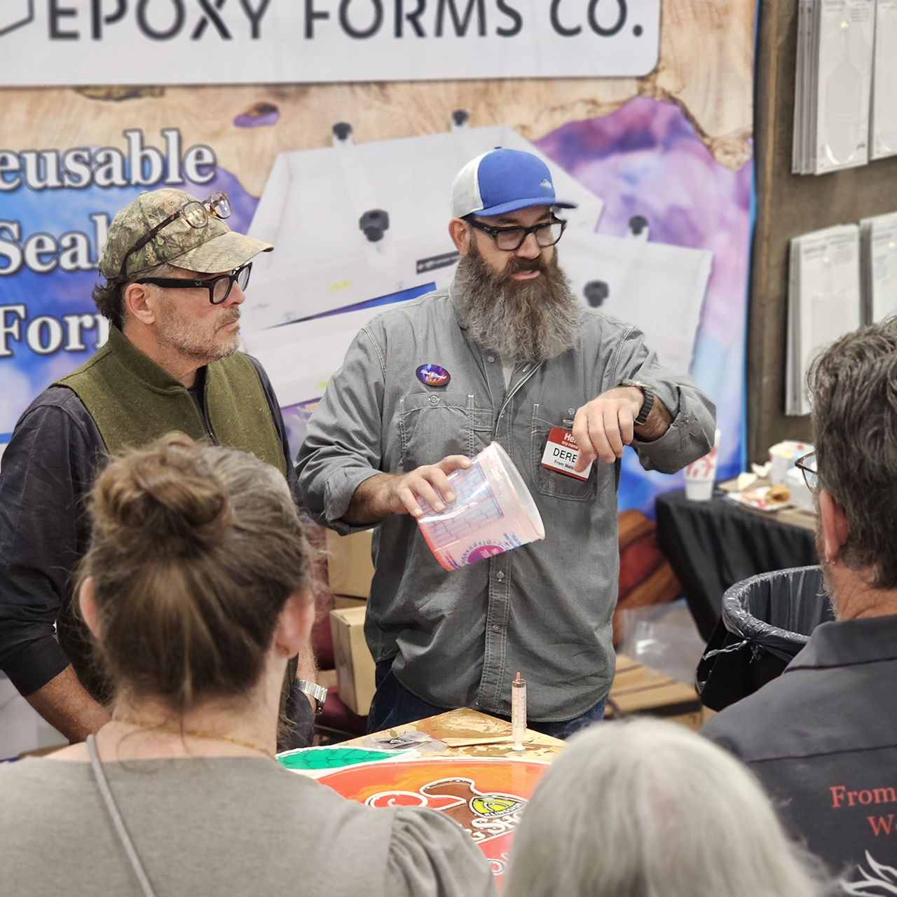 Two men demonstrating epoxy forms at a trade show.