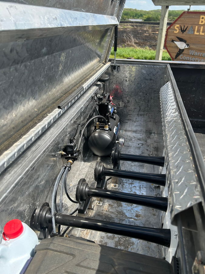 Overhead view open diamond-plate toolbox showing four black horn trumpets air tank compressor solenoid and wiring Conductor's Special 127H in Kyle's 1985 Chevy K20 bed gallery photo 3