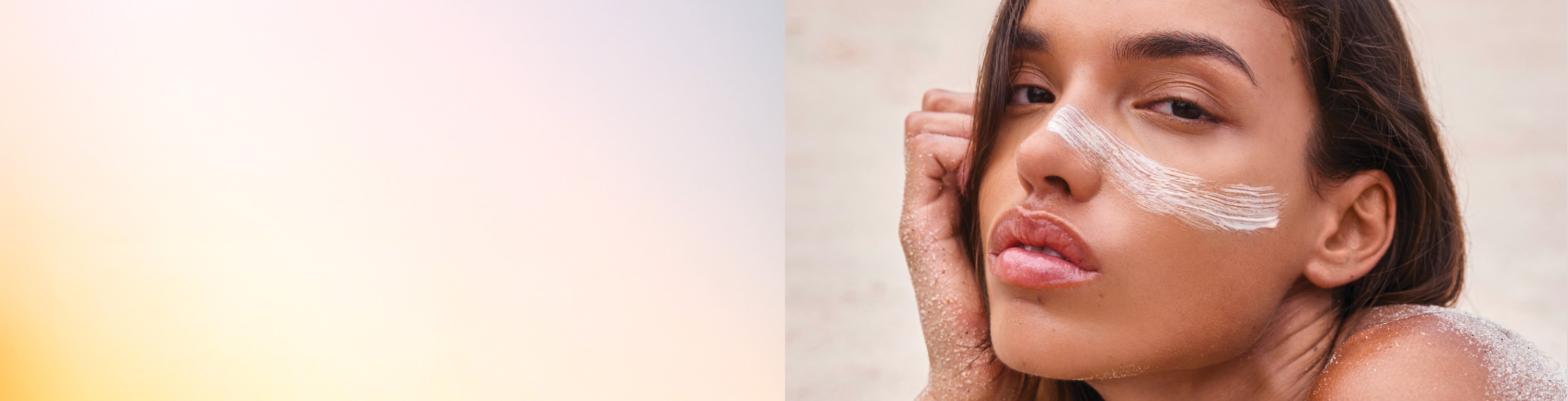 Woman applying skincare product on her face in a bright setting.
