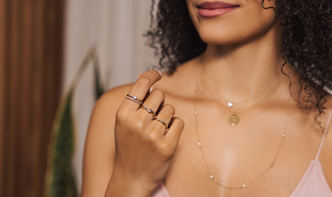 woman displaying stacked rings on her hand including rings that are accented, solid and with a center stone